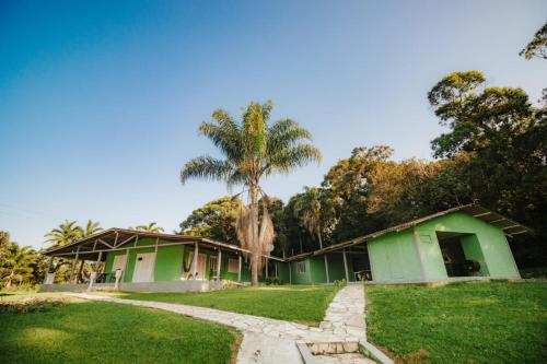 a green building with a palm tree behind it at Suítes Romanetto com Piscina e Vista - Antonina in Antonina