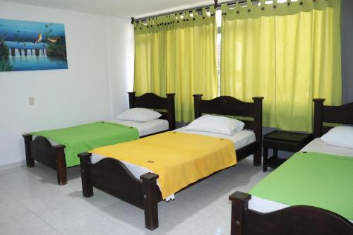 een kamer met drie bedden met geel en groen bij Hotel Inambu in Villavicencio