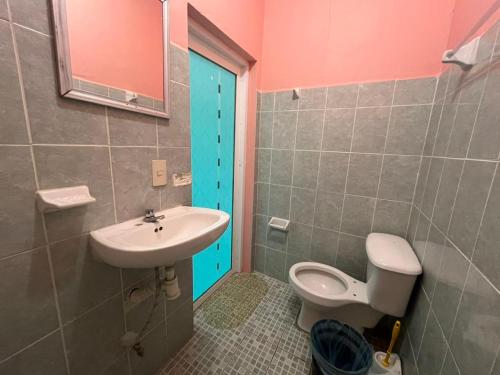 a bathroom with a sink and a toilet and a blue door at Posada Isis in Catemaco