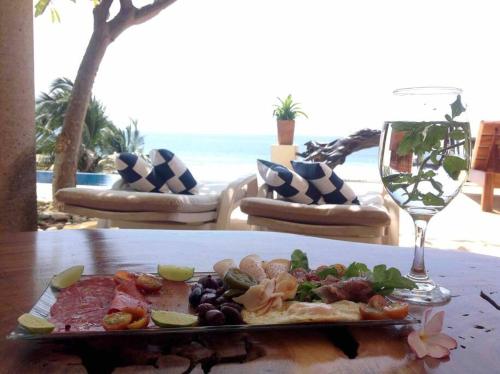 Casa Conti Agua Blanca في Playa Agua Blanca: طبق من الطعام على طاولة مع كوب من النبيذ