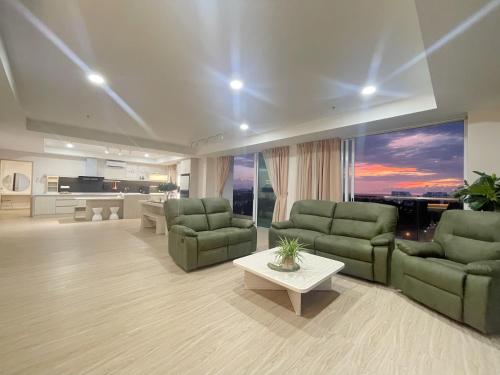 a living room with two green couches and a table at QUEENSLAND SUITES at Aru Suites, Kota Kinabalu in Kota Kinabalu