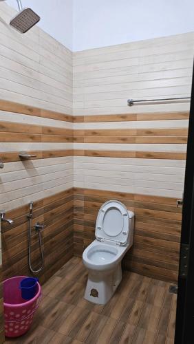a bathroom with a toilet with wooden walls and a basket at The Star Resorts in Vagamon