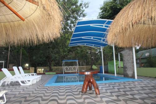 a pool with a blue umbrella and chairs and a table at Cabaña del lago in Ciudad del Este