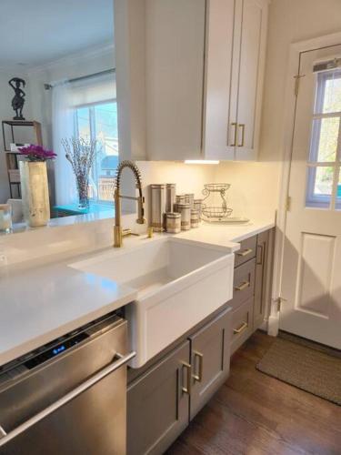 a white kitchen with a sink and a window at Daisy's Heavenly Townhome in Alexandria