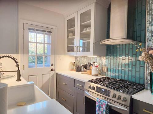 a kitchen with white cabinets and a stove top oven at Daisy's Heavenly Townhome in Alexandria