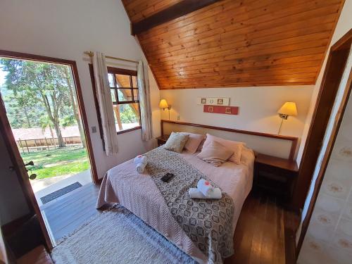 um quarto com uma cama e uma grande janela em Recanto das Hortencias Hotel em Monte Verde