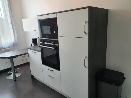 eine Küche mit weißen Schränken, einer Mikrowelle und einem Tisch in der Unterkunft Appartement F3 de 60M² à 20 minutes de Paris. in Yerres