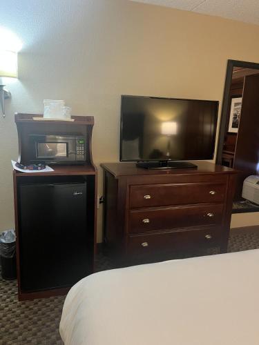 a hotel room with a bed and a tv and a dresser at Woodmen Inn in Colorado Springs