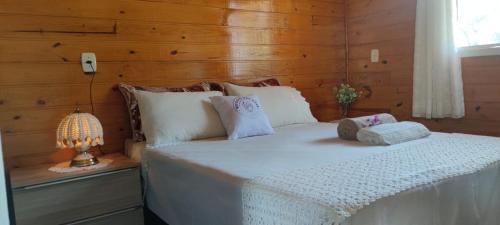 a bedroom with a white bed with a wooden wall at Refúgio das Uvas * Casa do Lago in Frederico Westphalen