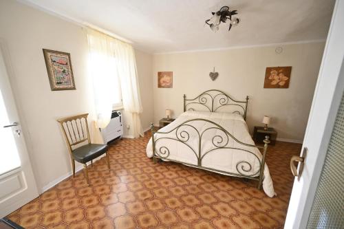 a bedroom with a white bed and a chair at CASA LETIZIA in Ozzano Monferrato