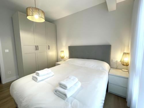 Un dormitorio con una cama blanca con toallas. en ByAndreea Apartaments EtxeBat, en Guernica y Luno