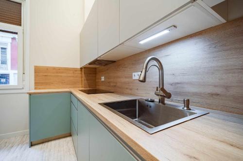 cocina con fregadero de acero inoxidable y pared de madera en Espacio Colmenares en Valladolid