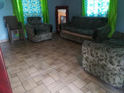 ein Wohnzimmer mit Sofas, Stühlen und grünen Vorhängen in der Unterkunft Cabaña Don Chacon in Paso Ancho