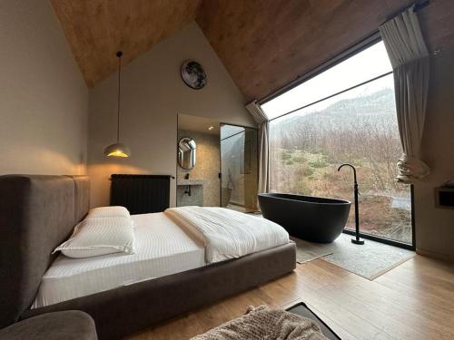 um quarto com uma grande janela e uma banheira em North Alpine Villas em Bogë