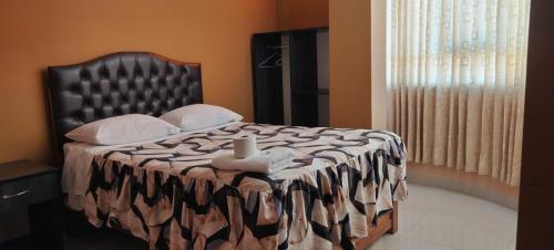 un letto con una coperta bianca e nera e una finestra di HOSTAL LLAUT * * a Moquegua