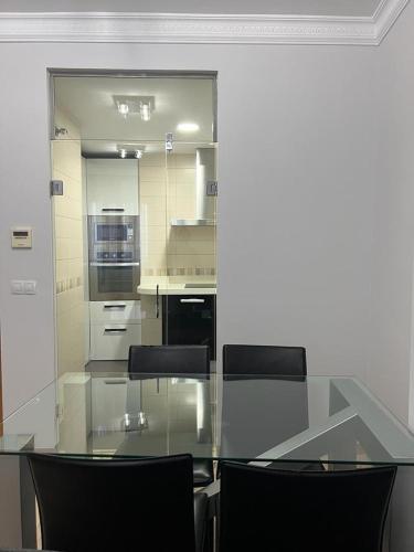 a kitchen with a glass table and black chairs at Apartamento La Muralla II in Baena