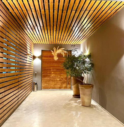 a hallway with a wooden ceiling and two potted plants at Villa Jardins D'Isa in Marrakech