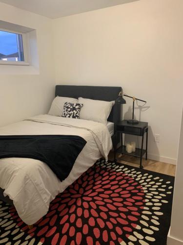 Schlafzimmer mit einem Bett und einem roten und weißen Teppich in der Unterkunft Cheerful and cozy 1 bedroom,separate entrance in Winnipeg