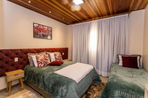a bedroom with two beds and a window at Pousada Geada de Campos in Campos do Jordão
