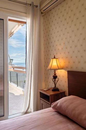 a bedroom with a bed and a window with a balcony at Sea view apartment 100m from the beach in Saronida