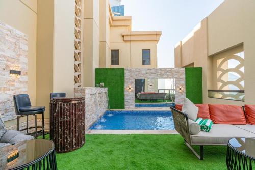 une cour avec une piscine et de l'herbe verte dans l'établissement ELAN RIMAL SADAF Suites, à Dubaï