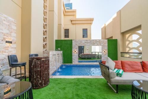 un patio trasero con piscina y césped verde en ELAN RIMAL SADAF Suites, en Dubái
