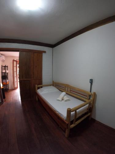 um quarto com uma cama e um armário de madeira em Morada da Xica em Guarda do Embaú