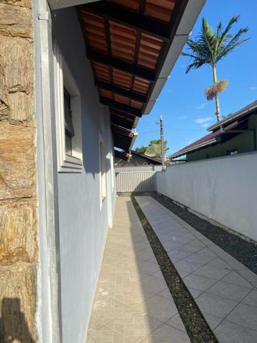 a building with a sidewalk next to a wall and a palm tree at Casa da Cris in Penha