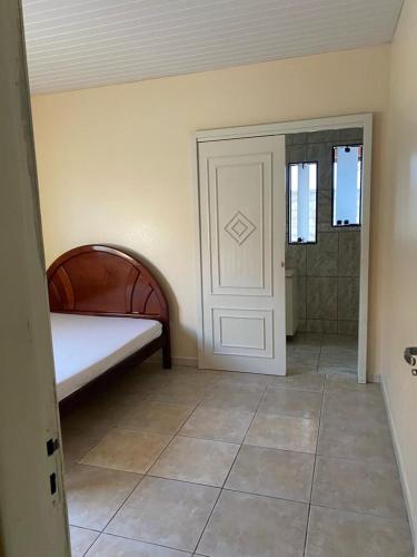 a bedroom with a bed and a door and a tile floor at Casa da Cris in Penha
