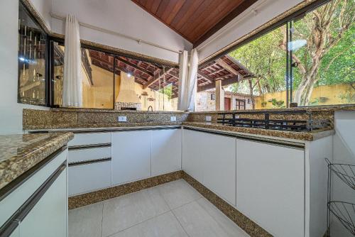 cocina con armarios blancos y ventana grande en 151 - Casa Triplex apenas a 80m da Praia de Bombas, en Bombinhas