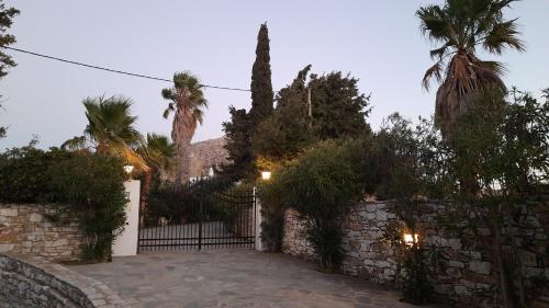 a stone fence with a gate and palm trees at Villa Themis in Káto Sangríon