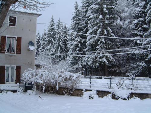 a snow covered yard with a house and trees at Maison Neuve Grandval in Grandval