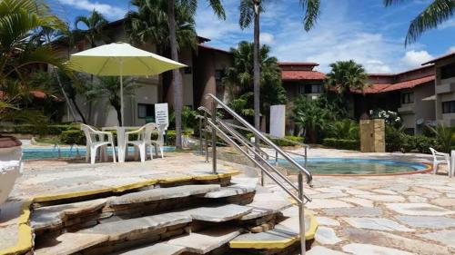 een patio met een tafel en een parasol naast een zwembad bij Recanto das Águas Apart in Rio Quente