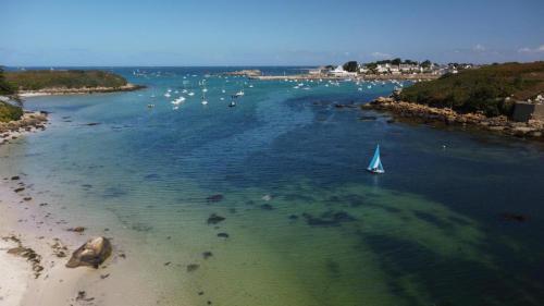 a small sailboat in the water next to a beach at Villa Plain-Pied Vue Mer in Lanildut