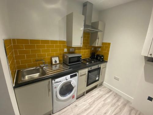 una pequeña cocina con fregadero y lavadora en Entire 1x Bed flat en Bolton