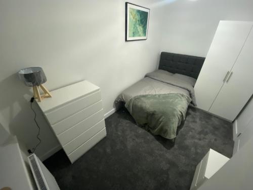 um pequeno quarto com uma cama e uma cómoda em Entire 1x Bed flat em Bolton