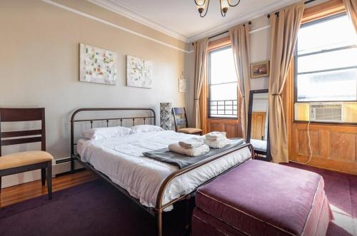Schlafzimmer mit einem Bett, einem Stuhl und Fenstern in der Unterkunft Amazing 3 Bedroom Apartment in New York