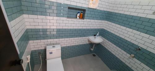 W łazience wyłożonej niebiesko-białymi kafelkami znajduje się umywalka. w obiekcie a LoFT w mieście Alappuzha