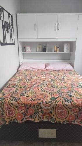 a bed with a colorful blanket on top of it at Apartamento aconchegante com ar condicionado de 22 a 8h in Rio de Janeiro