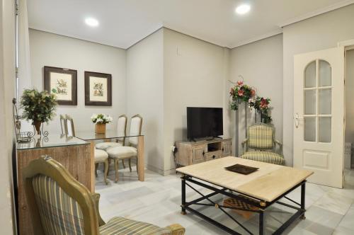 a living room with a table and a tv at Apartamentos Alfonso XIII in Córdoba