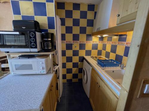 une petite cuisine avec un micro-ondes et un évier dans l'établissement Studio chaleureux 19m² pour 3 personnes, balcon sud, pied des pistes, Preyerand, Les Menuires - FR-1-452-251, aux Menuires