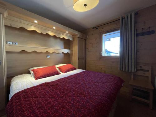 Schlafzimmer mit einem Bett mit roten Kissen und einem Fenster in der Unterkunft Appartement Saint-Martin-de-Belleville, 4 pièces, 6 personnes - FR-1-452-133 in Saint-Martin-de-Belleville