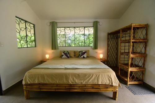 a bedroom with a large bed with two windows at Jungle Passion Lodge in Ojochal