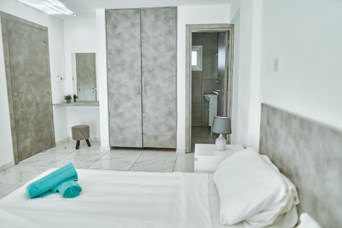a white bedroom with a bed and a bathroom at Nissi Avenue Suites in Ayia Napa