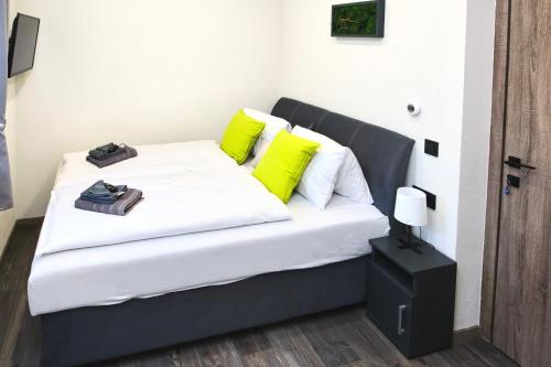a bed with yellow and white pillows in a room at Holdruta Vendégház in Kunfehértó