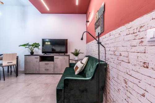 uma sala de estar com um sofá verde contra uma parede de tijolos em Tartini Lofts em Bolonha