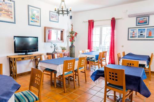 a dining room with tables and chairs and a tv at Complejo Los Veneros in Santa Ana la Real