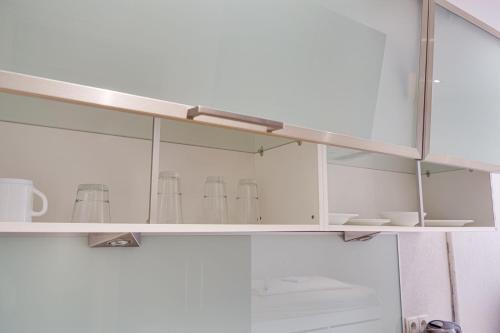 - un meuble blanc avec des portes en verre et des tasses dans l'établissement Micro Studio Apartment MINIMUM 30 DAYS, à Innsbruck