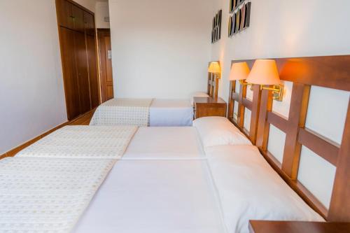 two beds in a room with two lamps at Complejo Los Veneros in Santa Ana la Real