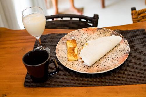 a table with a plate of food and a glass of milk at Suíte villa rota milagres, aconchegante & completa in São Miguel dos Milagres
